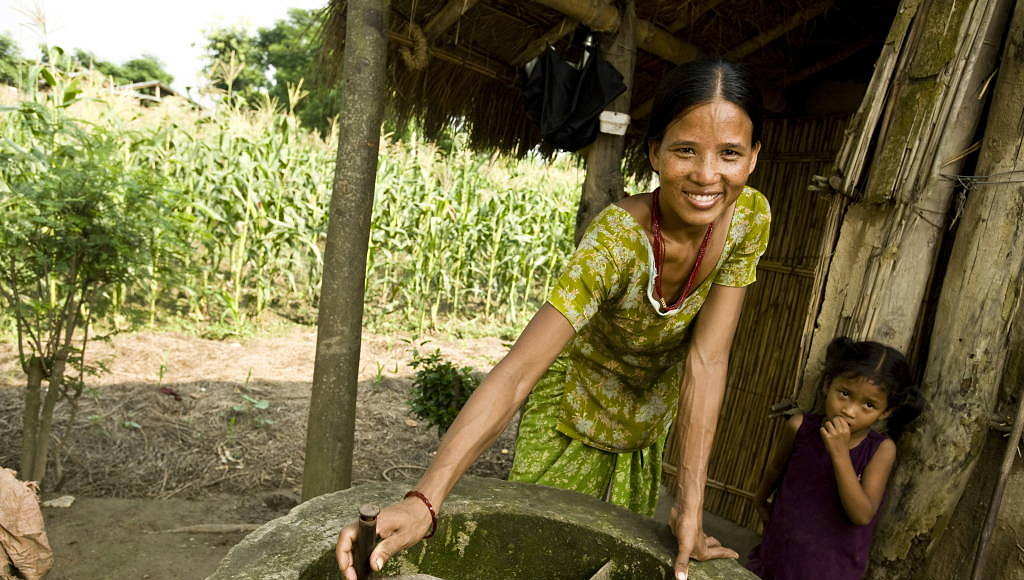 A woman turns the manure stirrer outside her home in a bio gas village on the outskirts of Chitwan National Park, Nepal : Photo © Simon de Trey-White / WWF-UK