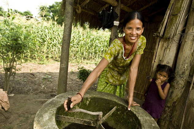 A woman turns the manure stirrer outside her home in a bio gas village on the outskirts of Chitwan National Park, Nepal : Photo © Simon de Trey-White / WWF-UK