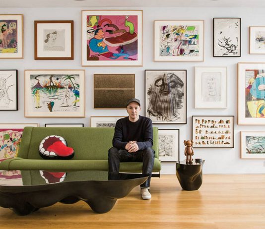KAWS sitting in front of his extensive art collection : Photo by © Stefan-Ruiz