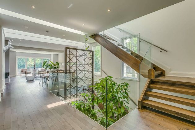 Garden Void House - Vista Interior desde el Nivel principal. Esta vivienda adopta una compleja relación entre su masa y el vacío al interconectar el Jardín desde el sótano hasta el segundo nivel a través de un Vacío. "El vacío comparte un viaje interno a través de la edificación" Photo credit © Navid Aali