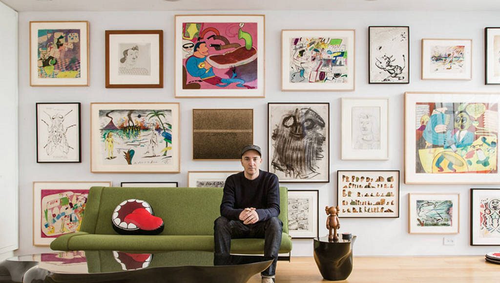 KAWS sitting in front of his extensive art collection : Photo by © Stefan Ruiz