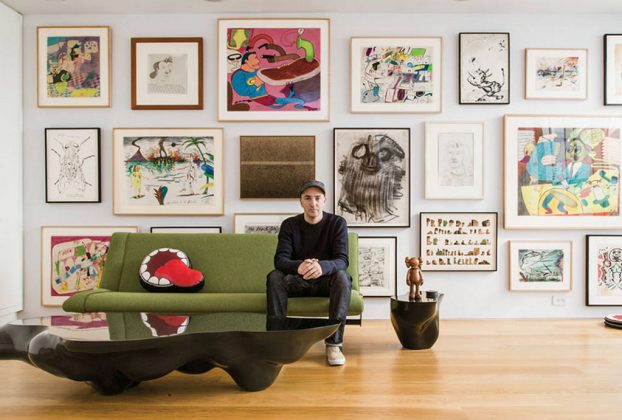 KAWS sitting in front of his extensive art collection : Photo by © Stefan Ruiz