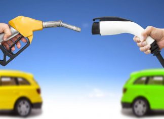 Automóvil eléctrico y auto concepto de gasolina. mano sosteniendo bomba de gasolina y conector para recarga de energía vía Shutterstock