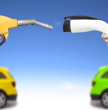 Automóvil eléctrico y auto concepto de gasolina. mano sosteniendo bomba de gasolina y conector para recarga de energía vía Shutterstock
