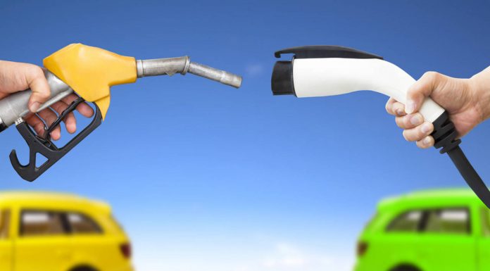Automóvil eléctrico y auto concepto de gasolina. mano sosteniendo bomba de gasolina y conector para recarga de energía vía Shutterstock