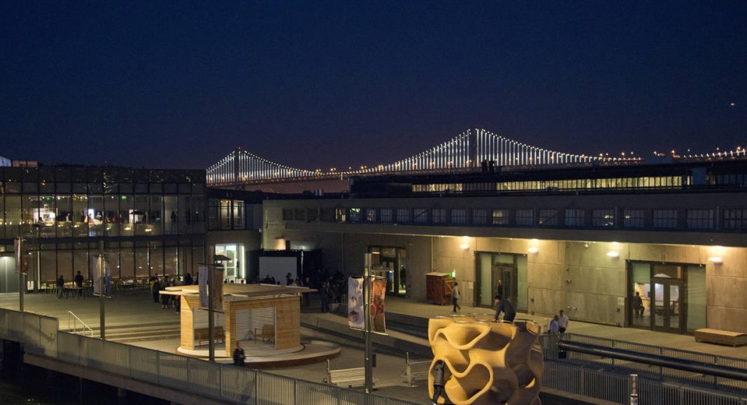 La Galería al Aire Libre del Exploratorium de noche. La Galería al Aire Libre cuenta con 6,070 m2 de espacios cívicos gratuitos que presetan exposiciones, así como también con 2.023 m2 de espacios con boleto que incluyen exhibiciones, mostrado en esta imagen. El Proyecto Bay Lights Project en el Puente de la Bahía de San Francisco-Oakland como fondo : Image by Amy Snyder © Exploratorium, www.exploratorium.edu