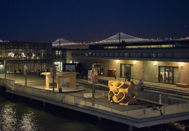 La Galería al Aire Libre del Exploratorium de noche. La Galería al Aire Libre cuenta con 6,070 m2 de espacios cívicos gratuitos que presetan exposiciones, así como también con 2.023 m2 de espacios con boleto que incluyen exhibiciones, mostrado en esta imagen. El Proyecto Bay Lights Project en el Puente de la Bahía de San Francisco-Oakland como fondo : Image by Amy Snyder © Exploratorium, www.exploratorium.edu