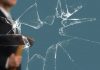 Business Man with Sledgehammer behind a broken Glass Pane vía Shutterstock
