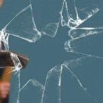 Business Man with Sledgehammer behind a broken Glass Pane vía Shutterstock