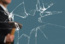 Business Man with Sledgehammer behind a broken Glass Pane vía Shutterstock