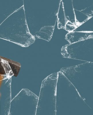Business Man with Sledgehammer behind a broken Glass Pane vía Shutterstock