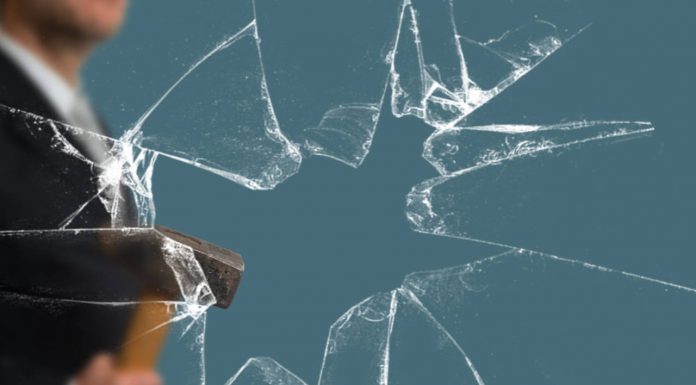 Películas Arquitectónicas para Ventanas LLumar para Protección y Seguridad Business Man with Sledgehammer behind a broken Glass Pane vía Shutterstock