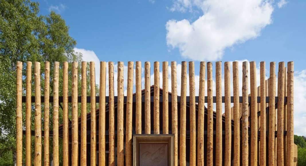 Logs cover the old school that has been painted black to appear only as a shadow behind the screen of timber : Photo credit © Åke E:son Lindman