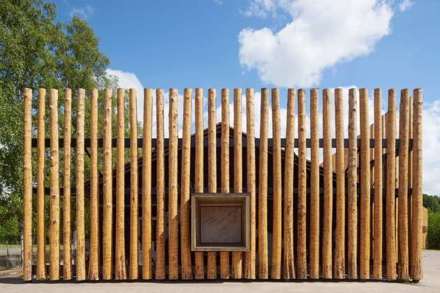 Logs cover the old school that has been painted black to appear only as a shadow behind the screen of timber : Photo credit © Åke E:son Lindman