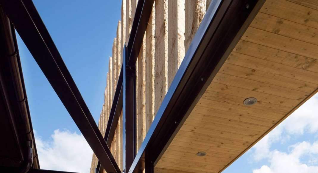 The screen of timber wraps around the building with openings for entry and extra sunlight intake. Protruding wooden boxes also provides space for benches, signage and artwork : Photo credit © Åke E:son Lindman