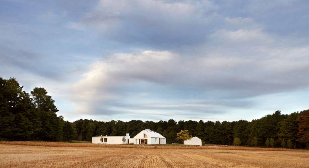 The house sits at the nexus of the land’s constituent characteristics: forests to the west, a hill to the south, and 100 acres of fields to the north and east : Photo credit © Ben Rahn / A-Frame Studio