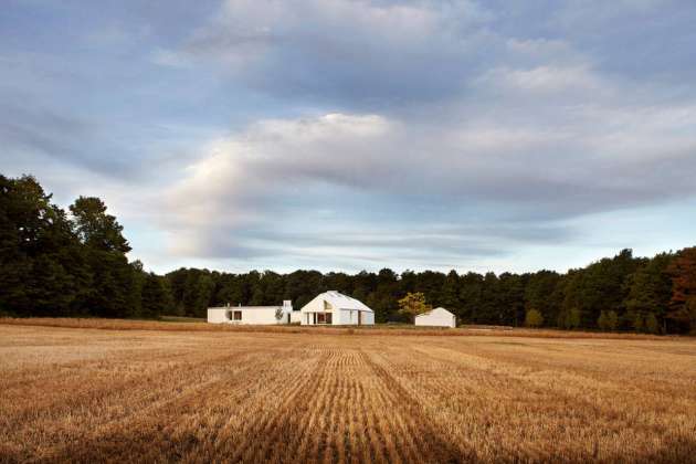 The house sits at the nexus of the land’s constituent characteristics: forests to the west, a hill to the south, and 100 acres of fields to the north and east : Photo credit © Ben Rahn / A-Frame Studio