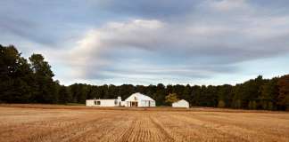 The house sits at the nexus of the land’s constituent characteristics: forests to the west, a hill to the south, and 100 acres of fields to the north and east : Photo credit © Ben Rahn / A-Frame Studio