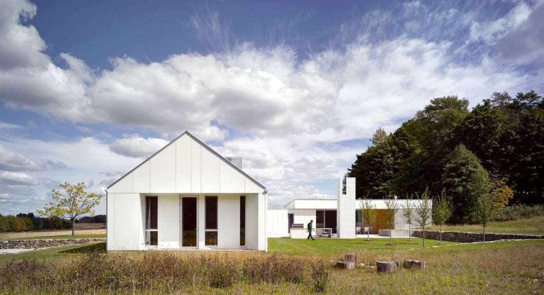 The white exterior helps register the seasons, distinct amidst the green fields of summer, and melding into a winter landscape of waning light and snow : Photo credit © Ben Rahn / A-Frame Studio