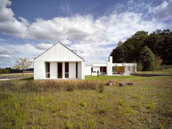 The white exterior helps register the seasons, distinct amidst the green fields of summer, and melding into a winter landscape of waning light and snow : Photo credit © Ben Rahn / A-Frame Studio