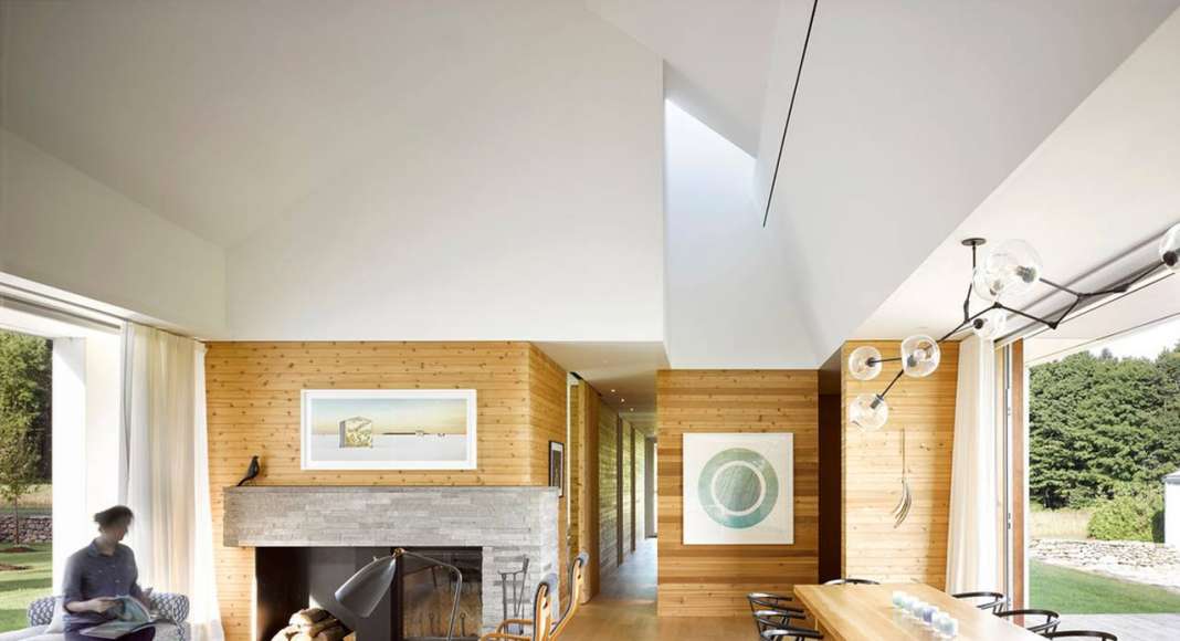 Inside, floors and walls made from white oak and knotty white cedar are textured and warm. In contrast, the ceiling above the main space is white, expansive and seemingly boundless. The distinct difference in materiality echoes the meeting of land and sky outside : Photo credit © Ben Rahn / A-Frame Studio