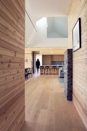 The warm oak and cedar floors and walls contrast beautifully with the rough texture of the stone fireplace and the carved geometries of the sculpturally articulated ceiling planes : Photo credit © Ben Rahn / A-Frame Studio