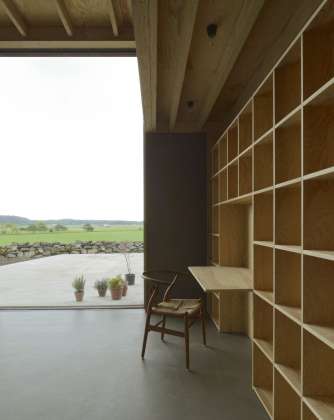 The north side of the living room with a built-in bookcase and glass opening to the wideopen landscape. : Photo © Bornstein Lyckefors Arkitekter